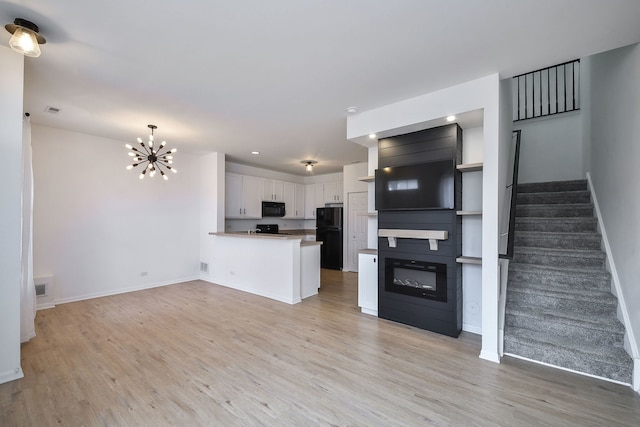 kitchen with a peninsula, black appliances, baseboards, and light wood-style floors