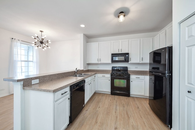 kitchen featuring black appliances, light wood finished floors, a sink, and white cabinetry