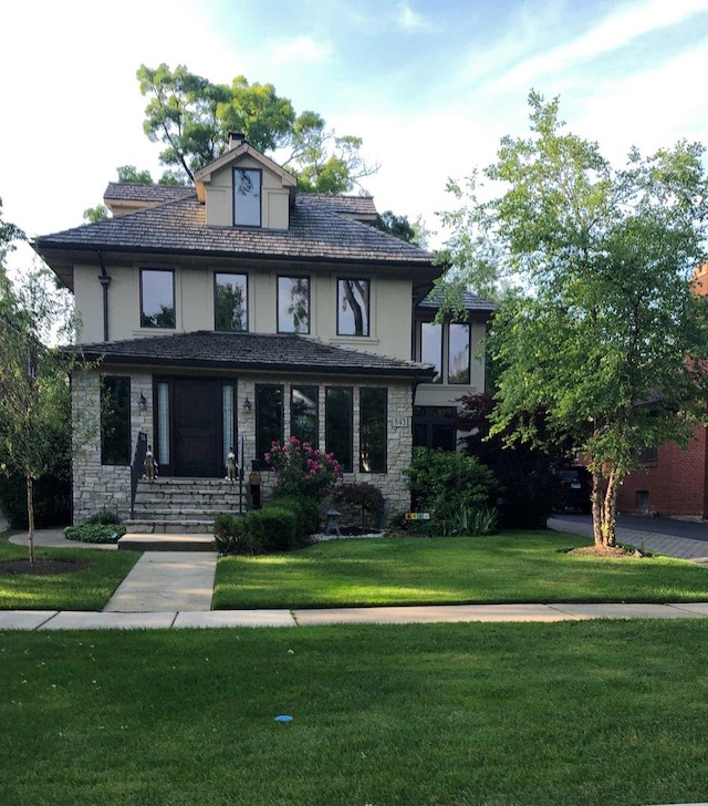 view of front of house featuring stone siding, stucco siding, and a front yard