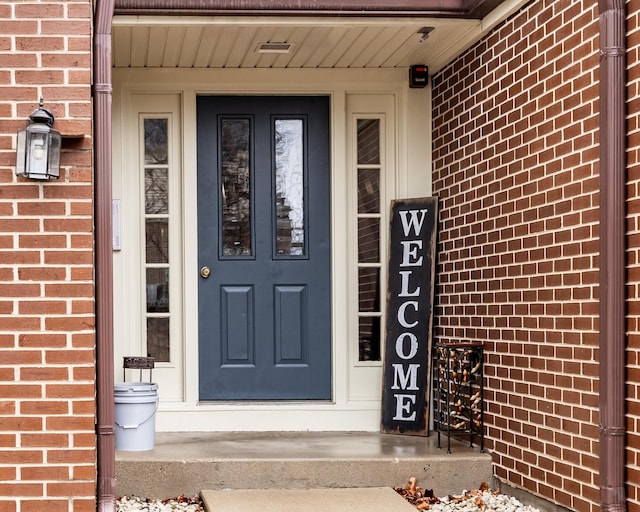 view of exterior entry featuring covered porch and brick siding