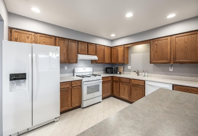 kitchen with white appliances, brown cabinetry, light floors, under cabinet range hood, and recessed lighting