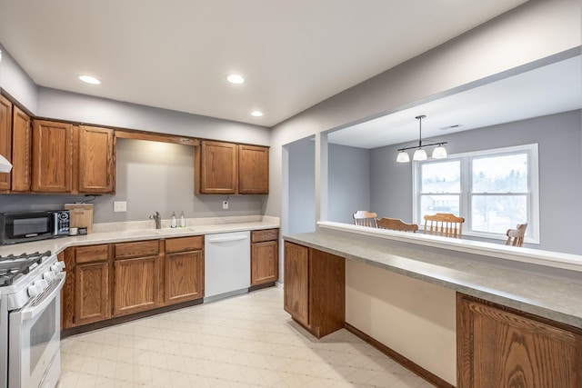 kitchen featuring white appliances, brown cabinetry, light floors, and recessed lighting