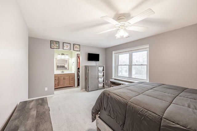 bedroom with baseboards, light carpet, ceiling fan, and ensuite bath