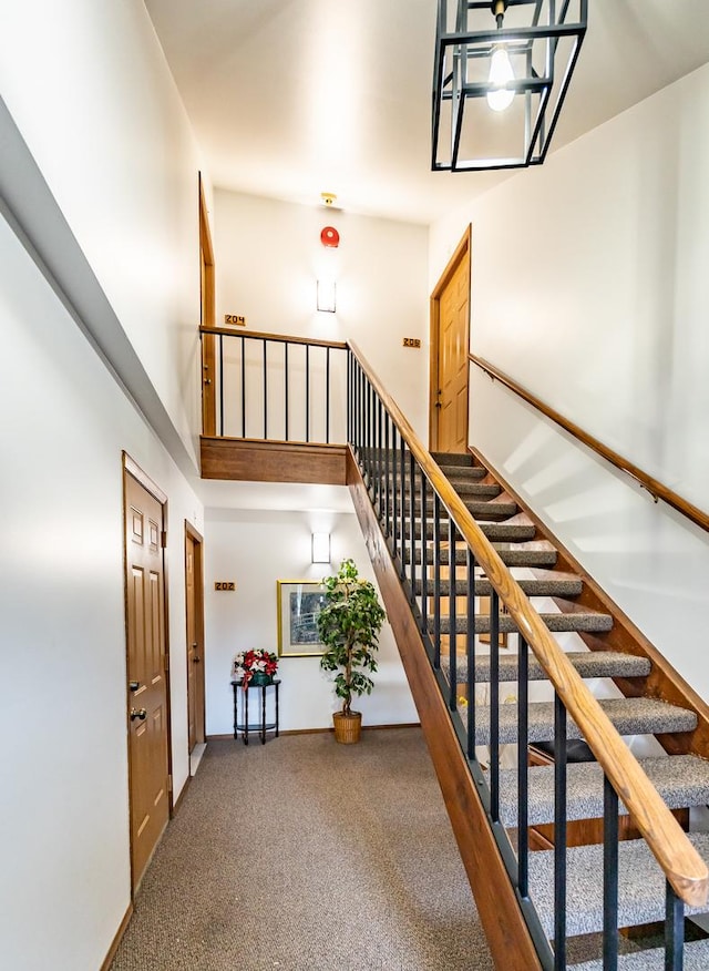 stairs with carpet floors and a towering ceiling