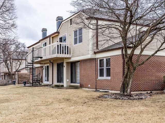 back of property with a yard, brick siding, a chimney, and stairway