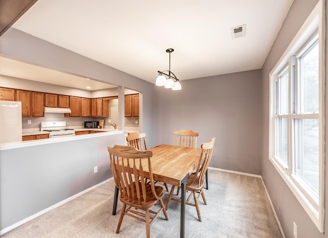 dining space with light carpet, an inviting chandelier, visible vents, and baseboards