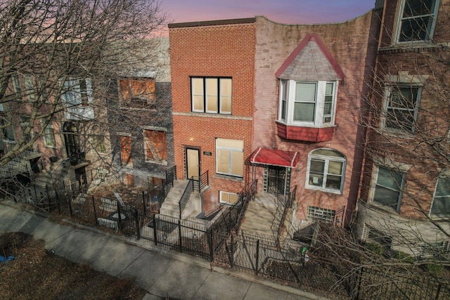 multi unit property featuring a fenced front yard and brick siding