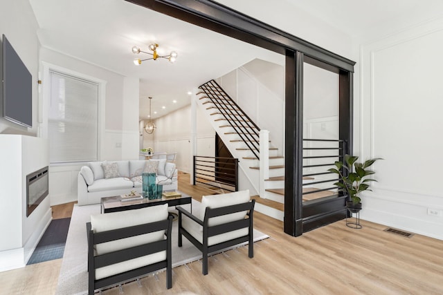 living room featuring a chandelier, a decorative wall, and stairs