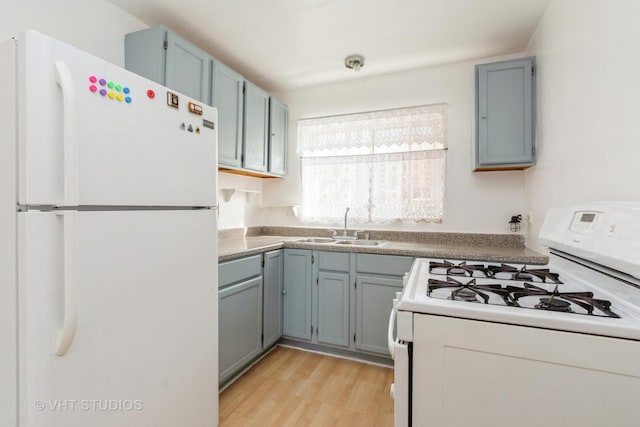 kitchen with a sink, white appliances, light wood-style flooring, and blue cabinetry