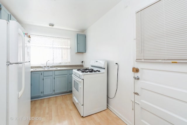 kitchen with light wood finished floors, white appliances, blue cabinets, and a sink