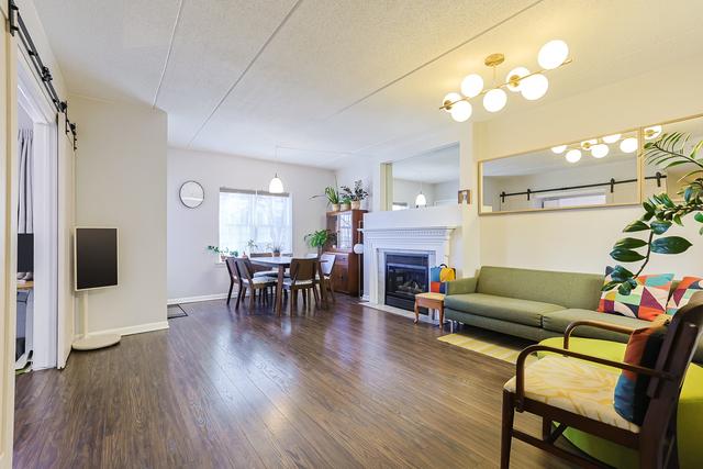 living room featuring a barn door, a fireplace with flush hearth, wood finished floors, and baseboards