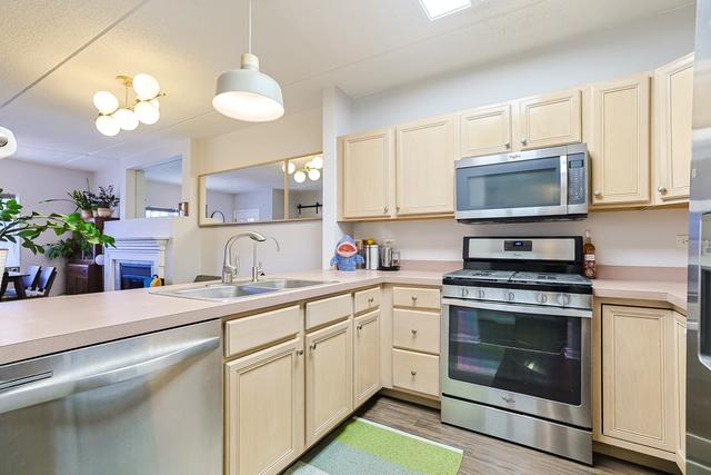 kitchen with a sink, appliances with stainless steel finishes, light wood-style flooring, and light countertops