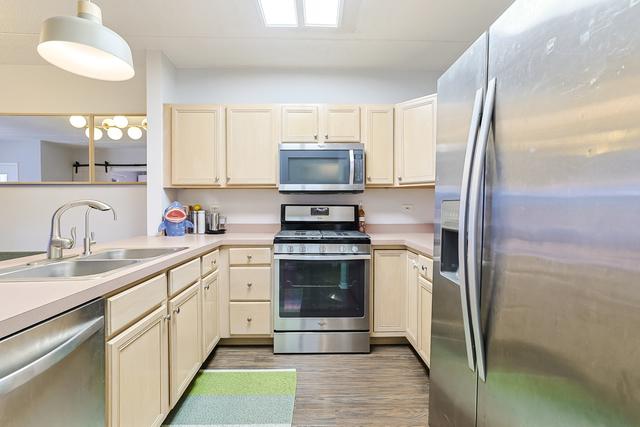 kitchen featuring a sink, appliances with stainless steel finishes, light wood finished floors, light countertops, and hanging light fixtures