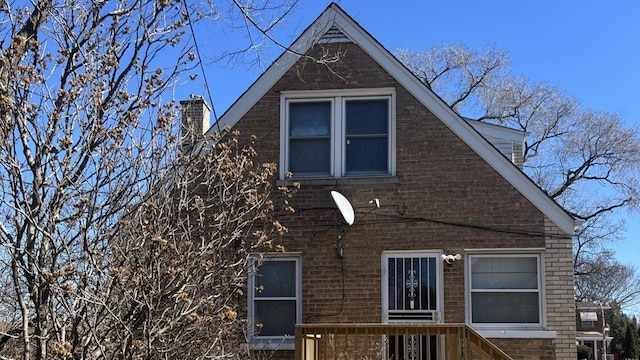 view of side of home featuring brick siding and a chimney