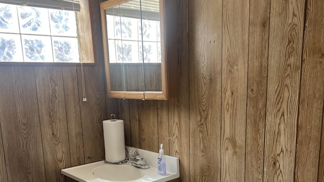 bathroom with wood walls and a sink