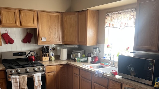 kitchen featuring a sink, light countertops, appliances with stainless steel finishes, decorative backsplash, and brown cabinets