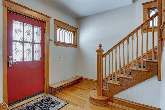 foyer featuring baseboards, stairway, and wood finished floors