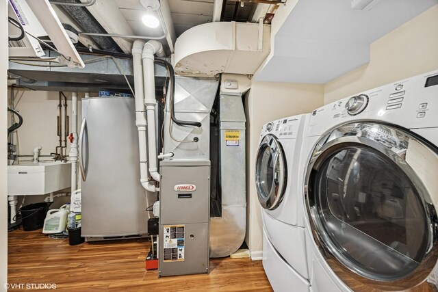 clothes washing area featuring a sink, wood finished floors, and washer and dryer