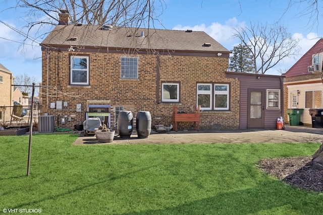 rear view of property featuring brick siding, a chimney, a lawn, a patio area, and cooling unit