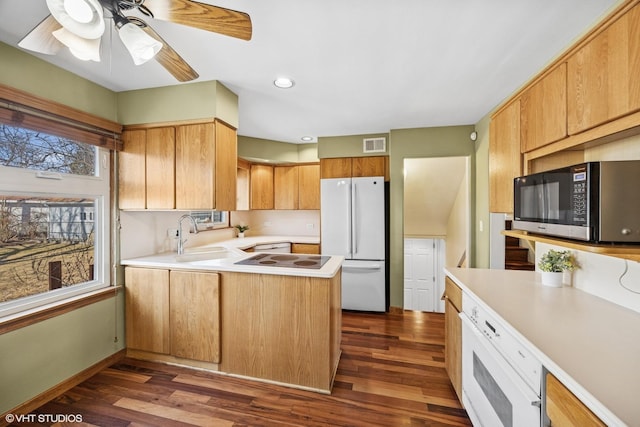 kitchen with visible vents, dark wood-style floors, freestanding refrigerator, a peninsula, and a sink