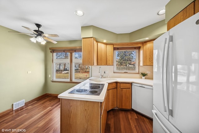 kitchen with dark wood-style floors, light countertops, visible vents, a sink, and white appliances