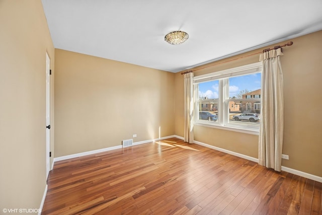 spare room with visible vents, baseboards, and wood finished floors