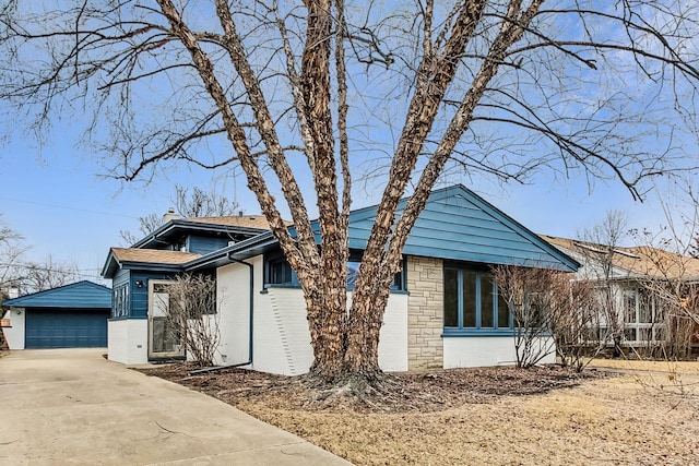 view of front facade featuring an outdoor structure, brick siding, a detached garage, and a shingled roof