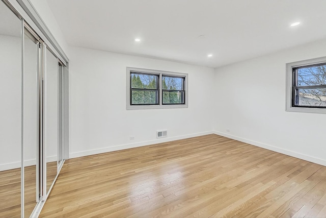 unfurnished bedroom featuring visible vents, multiple windows, and light wood-style floors