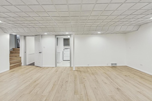 finished basement featuring visible vents, baseboards, stairs, and light wood finished floors