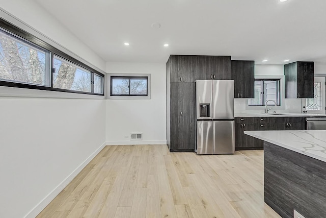 kitchen with baseboards, visible vents, a sink, appliances with stainless steel finishes, and light wood-type flooring