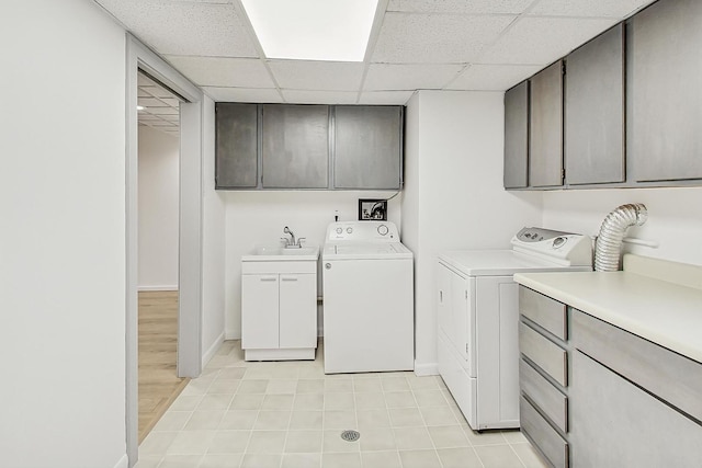 washroom with washer and dryer, cabinet space, baseboards, and a sink