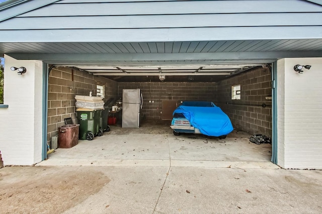 garage featuring concrete driveway and freestanding refrigerator