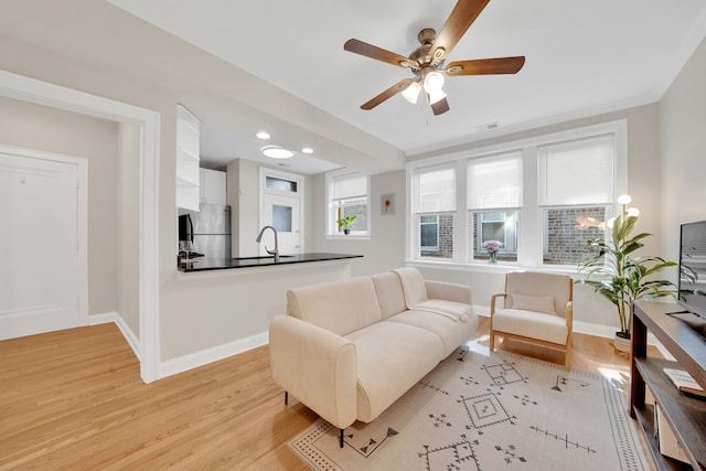 living room featuring visible vents, baseboards, a ceiling fan, and light wood finished floors