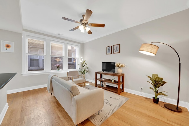 living area featuring visible vents, crown molding, baseboards, and wood finished floors