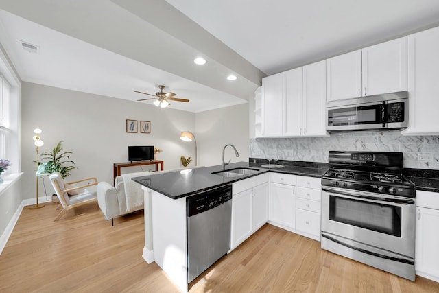 kitchen featuring visible vents, a sink, stainless steel appliances, a peninsula, and white cabinets