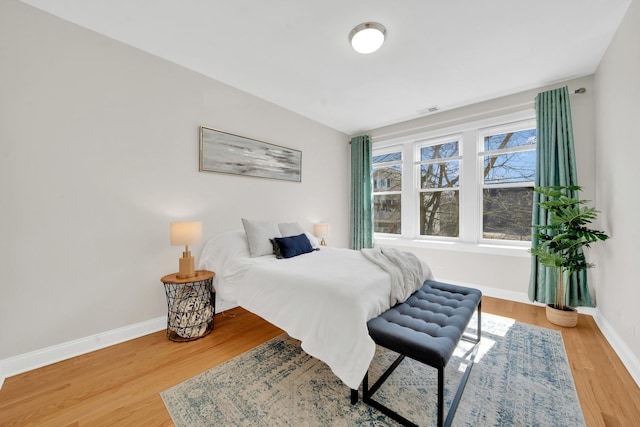 bedroom with wood finished floors, visible vents, and baseboards