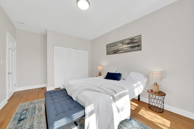 bedroom featuring a closet, visible vents, baseboards, and wood finished floors