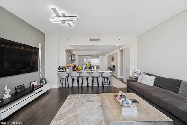 living room featuring visible vents, baseboards, baseboard heating, and dark wood-style flooring