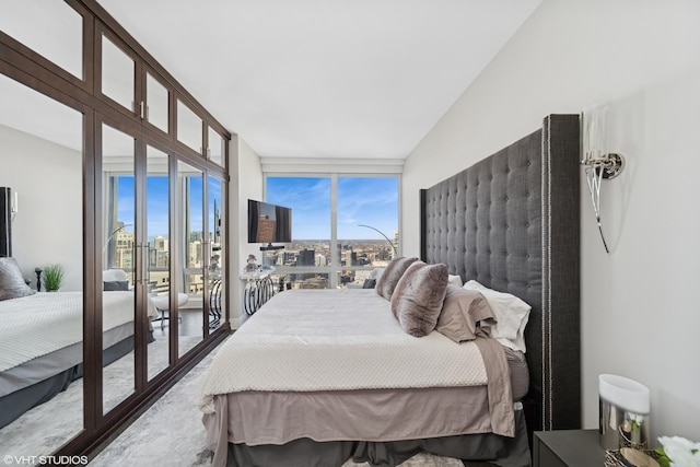 bedroom with multiple windows, a wall of windows, and access to outside