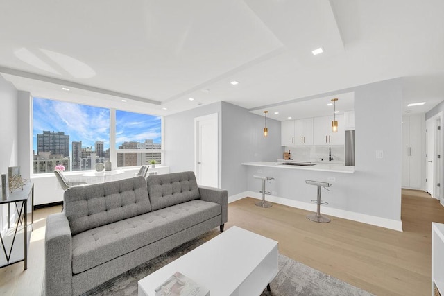 living area featuring a city view, light wood-style flooring, baseboards, and recessed lighting