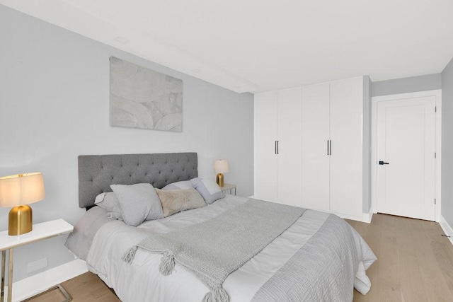bedroom with baseboards, a closet, and wood finished floors