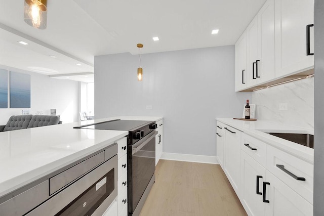 kitchen with light wood finished floors, range with electric cooktop, decorative light fixtures, light countertops, and recessed lighting