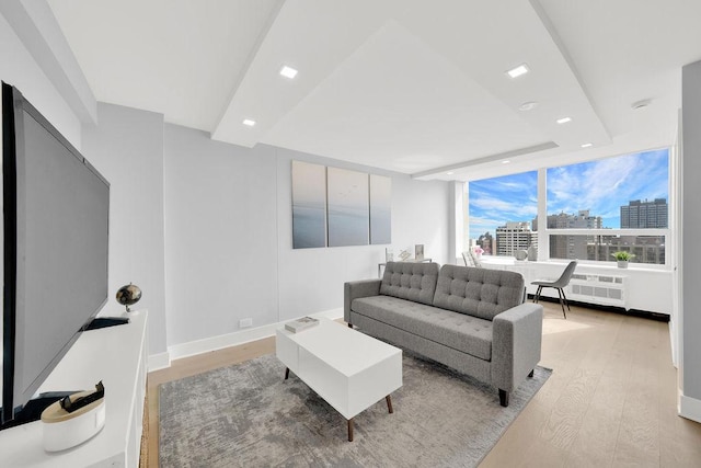 living area with recessed lighting, baseboards, radiator heating unit, a view of city, and light wood finished floors