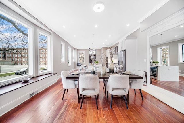 dining room with crown molding, baseboards, wine cooler, recessed lighting, and wood finished floors