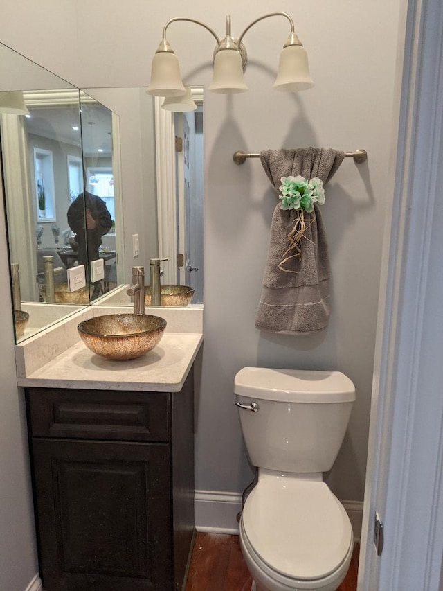 bathroom with baseboards, toilet, wood finished floors, and vanity