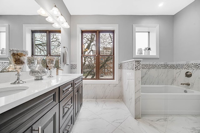 bathroom featuring a sink, marble finish floor, a bath, and double vanity