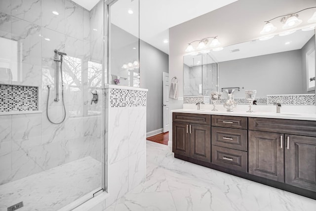 full bath with a sink, a marble finish shower, marble finish floor, and double vanity