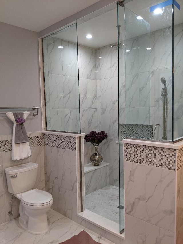 full bathroom featuring tile walls, toilet, marble finish floor, and a marble finish shower