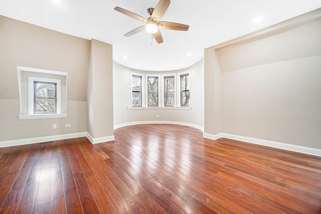 spare room featuring baseboards, wood-type flooring, and a healthy amount of sunlight