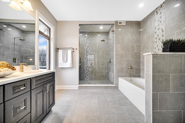 bathroom with a stall shower, recessed lighting, baseboards, a bath, and vanity